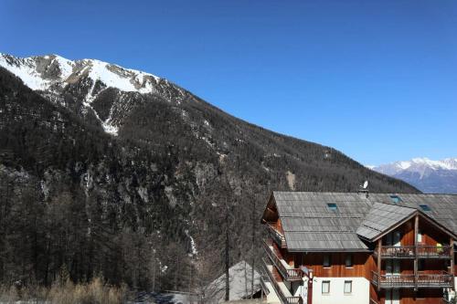un grand bâtiment avec une montagne en arrière-plan dans l'établissement Les Chalets De Bois Mean - Résidence le Bois Méan 2 pièces 4 personnes N°A307 MAE-0904, aux Orres
