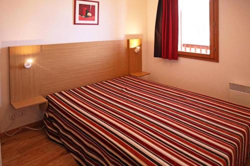 Ce lit se trouve dans un dortoir doté d'une couverture rayée. dans l'établissement Les Chalets De Bois Mean - Résidence le Bois Méan 2 pièces 4 personnes N°A307 MAE-0904, aux Orres