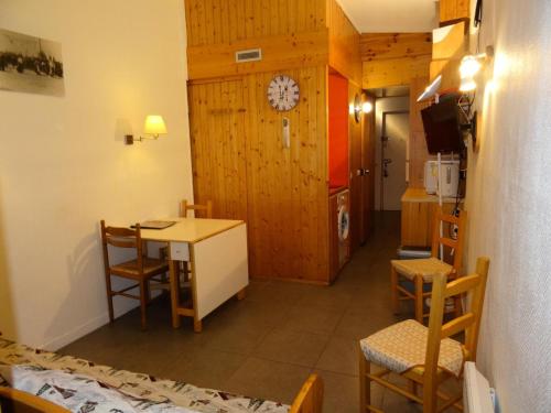Cette chambre comprend une table, des chaises et une horloge murale. dans l'établissement Résidence Grand Arbois - Studio 4 personnes au cœur de la station d'Arc 1800 dans le village des Villards, proche des pistes et des commerces MAE-1957, à Arc 1800