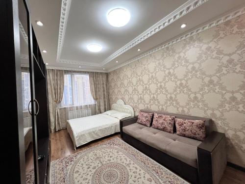 een woonkamer met een bank en een bed bij Apartmens in Complex Almaly 83-51 in Alma-Ata