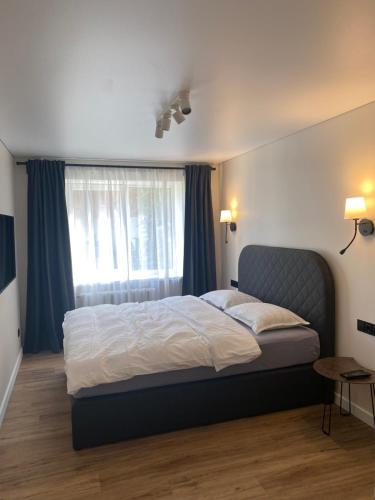 a bedroom with a bed and a window with blue curtains at Forentinn Vilniaus 23 in Panevėžys