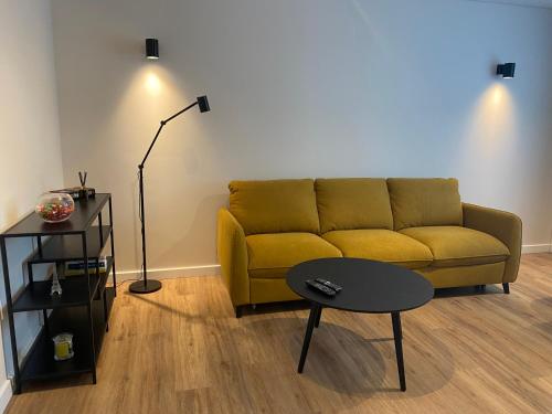 a living room with a yellow couch and a table at Forentinn Vilniaus 23 in Panevėžys