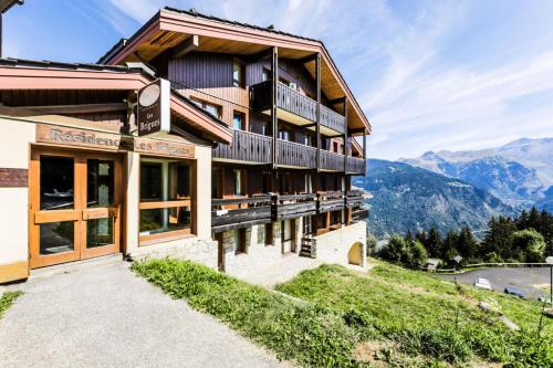 un bâtiment sur une colline avec des montagnes en arrière-plan dans l'établissement Résidence Les Brigues - maeva Home - Appartement 2 Pièces 6 Personnes – Confort MAE-4702, à Courchevel