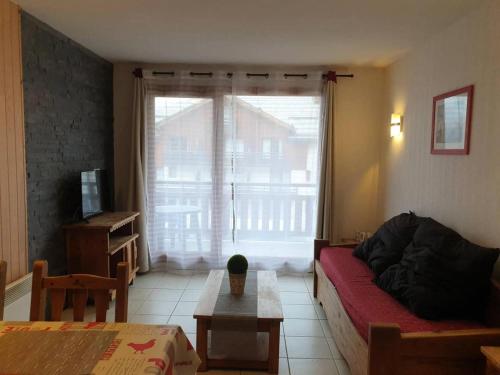 - un salon avec un canapé rouge et une grande fenêtre dans l'établissement Résidence Balcon Des Airelles - Balcon des Airelles N°206 MAE-0924, aux Orres