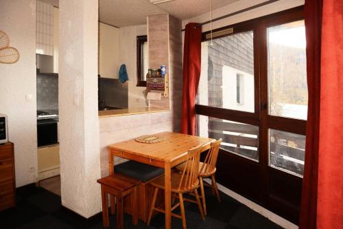 une cuisine avec une table et des chaises en bois ainsi qu'une fenêtre dans l'établissement Résidence La Seille - 12 LA SEILLE STUDIO 4 PERSONNES MAE-0974, aux Orres