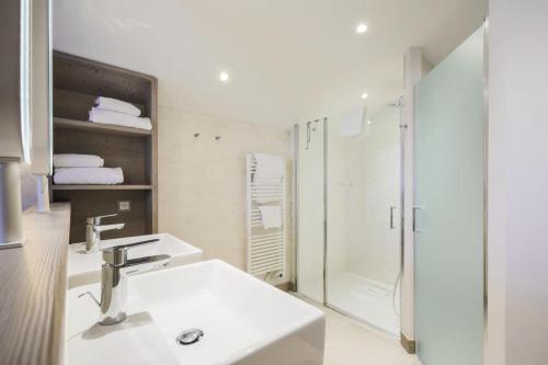 y baño blanco con lavabo y ducha. en Résidence Premium L'Hévana - maeva Home - Appartement 3 pièces 6 personnes 83, en Les Allues