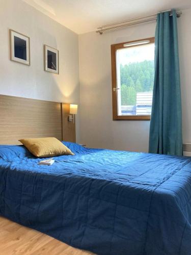 une chambre avec un lit bleu avec une fenêtre dans l'établissement Les Chalets De Bois Mean - Résidence le Bois Méan 2 pièces pour 6 personnes MAE-1064, aux Orres