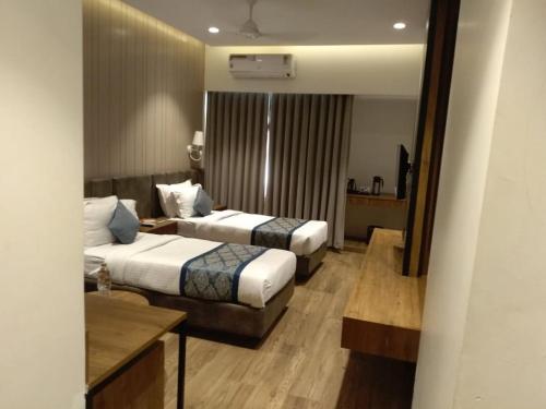 Habitación de hotel con 2 camas y mesa en Pinnacle Grand Hotel, en Ahmedabad