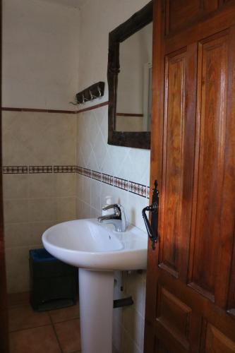 baño con lavabo blanco y puerta de madera en Casa rural para grupos en Ayora