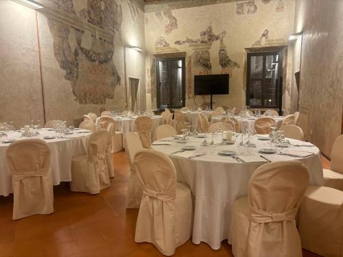 a room with white tables and chairs and a television at Cà Uberti Palace Hotel, MantegnaHotels in Mantova