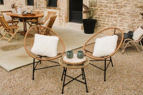 2 sillas de mimbre con almohadas blancas y mesa en gîte les Blés Dorés, en Corgengoux