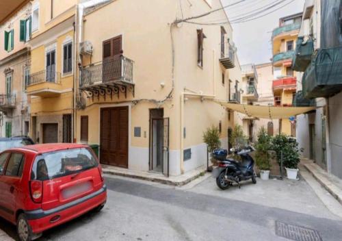a red car and a motorcycle parked on a street at Appartamenti Franco il Conte in Bagheria