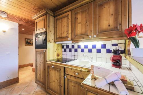 une cuisine avec des armoires en bois et un comptoir dans l'établissement Résidence Les Fermes de Méribel - maeva Home - Appartement 3 pièces 6 personnes Sélection MAE-7183, à Les Allues