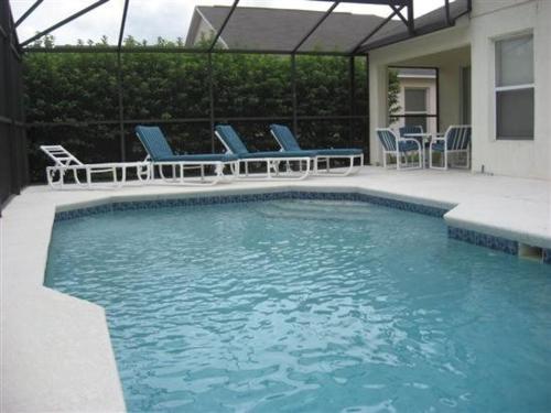 een zwembad met blauwe stoelen en een tafel en stoelen bij Five-Bedroom Pool Home Davenport in Davenport