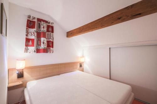 - une chambre avec un lit blanc et une peinture murale dans l'établissement Résidence les Chalets D'aurouze - maeva Home - Appartement 2 Pièces 4 Perso 01, à Saint-Étienne-en-Dévoluy