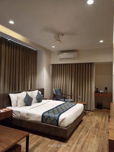 a bedroom with a bed and a desk and a chair at Pinnacle Grand Hotel in Ahmedabad