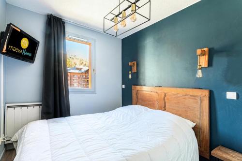 une chambre avec un lit et un mur bleu dans l'établissement Résidence L'Albane - maeva Home - Appartement moderne 2 pièces 6 personnes - Prestige - super Home MAE-1818, à Vars