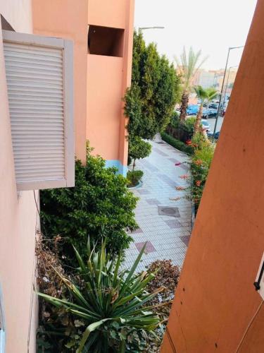 a building with a window and a sidewalk with plants at Julie's AIRPORT Apartment in Marrakech