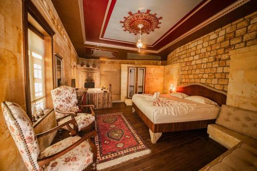 a bedroom with a bed and chairs in a room at Sunak Cave Hotel in Urgup