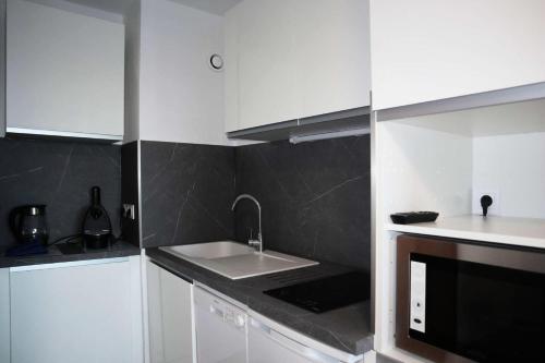 une cuisine blanche avec un évier et un micro-ondes dans l'établissement Résidence Les Cembros - Studio équipé pour 4 personnes MAE-1974, à Le Mélézet