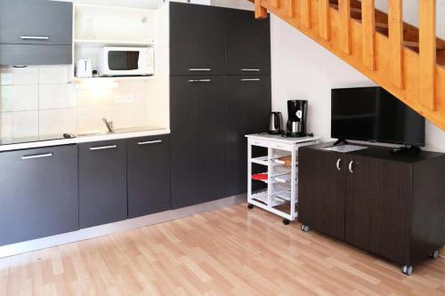 une cuisine avec des placards noirs, un évier et une télévision. dans l'établissement Résidence Les Terrasses Du Soleil D'or - 1107 TERRASSES DU SOLEIL D'OR, LES ORRES 1800 MAE-6774, aux Orres