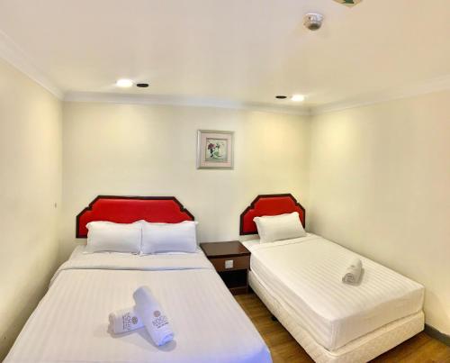 two beds in a room with red and white at Sogo Hotel 2 in Labuan