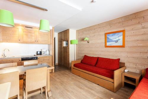 un salon avec un canapé rouge et une cuisine dans l'établissement Résidence Le Christiana - maeva Home - Appartement 2 Pièces 5 Personnes - Sélection MAE-3644, à Saint-Bon-Tarentaise