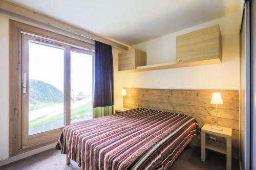 une chambre d'hôtel avec un lit et une grande fenêtre dans l'établissement Résidence Les Gémeaux - maeva Home - Appartement 2 pièces 5 personnes - Confort MAE-3621, à La Plagne Tarentaise