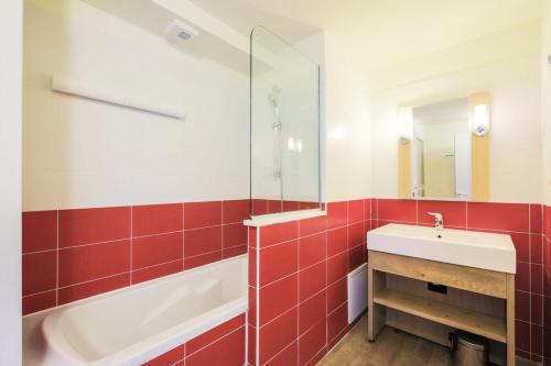 La salle de bains est pourvue de carrelage rouge, d'un lavabo et d'une baignoire. dans l'établissement Résidence Les Gémeaux - maeva Home - Appartement 2 pièces 5 personnes - Confort MAE-3621, à La Plagne Tarentaise