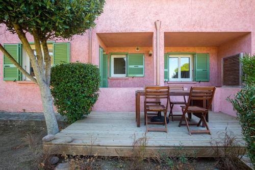 a wooden porch with chairs and a table in front of a pink house at Résidence Padro in Calvi