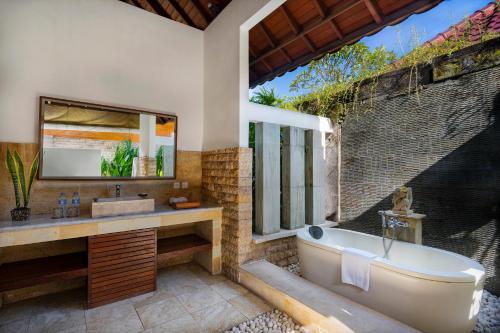 a bathroom with a tub and a sink and a window at Bali Prime Villas in Seminyak