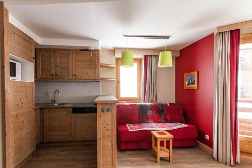 un salon avec un canapé rouge et une cuisine dans l'établissement Résidence Le Christiana - maeva Home - Appartement 2 Pièces 8 Personnes - Sélection MAE-4616, à Saint-Bon-Tarentaise