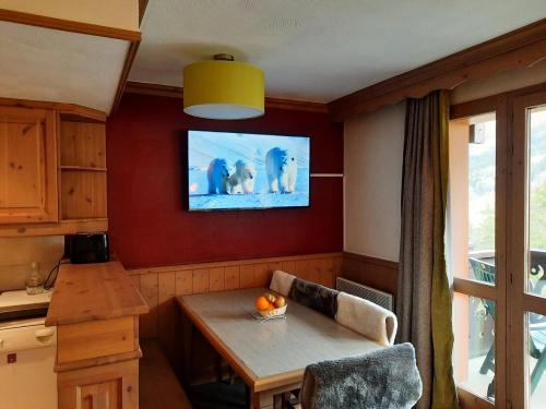 Il comprend une cuisine avec une table et une télévision murale. dans l'établissement Quartier La Forêt - maeva Home - Appartement 2 Pièces 6 Personnes - Sélection MAE-5474, à Valmorel