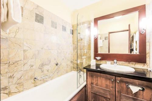 une salle de bain avec un lavabo, une baignoire et un miroir dans l'établissement Résidence Les Arcs 1950 Le Village - maeva Home - Appartement 2 Pièces 4 Personnes - Sélection MAE-5479, à Bourg-Saint-Maurice