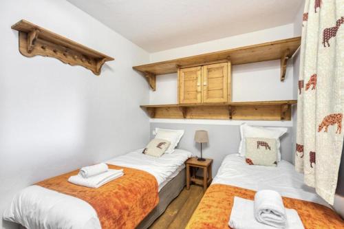 2 Einzelbetten in einem Zimmer mit weißen Wänden in der Unterkunft Résidence Les Fermes du Soleil - maeva Home - Appartement 3 Pièces 6 Personnes - Sélection MAE-6505 in Les Carroz d'Araches