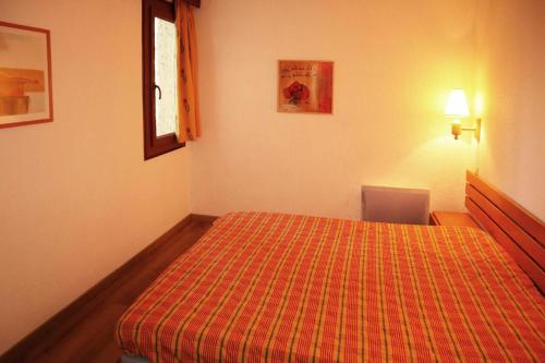 - une chambre avec un lit et une couverture orange dans l'établissement Résidence Le Belvedere - 2 Pièces pour 6 Personnes 864, à Le Mélézet