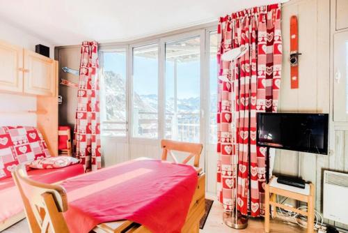 une chambre avec un rideau rouge et blanc et une table dans l'établissement Résidence Les Ruches - maeva Home - Studio 2 Personnes - Confort - Bâtiment Allegro MAE-7437, à Avoriaz