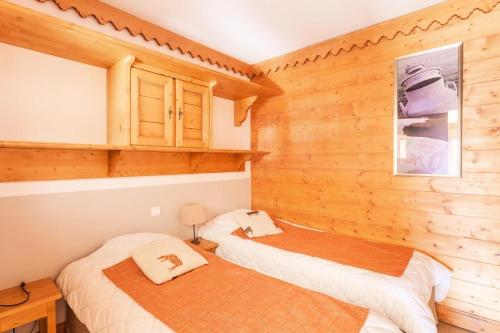 deux lits dans une chambre aux murs en bois dans l'établissement Résidence Les Hauts Bois - maeva Home - Appartement 3 Pièces 6 Personnes - Sélection MAE-7828, à Aime La Plagne