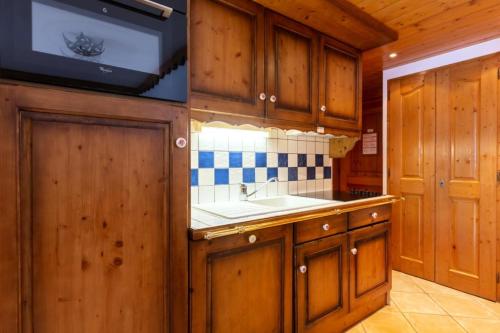 a kitchen with wooden cabinets and a sink at Résidence Les Fermes du Soleil - maeva Home - Appartement 3 pièces 6 person 04 in Les Carroz d'Araches