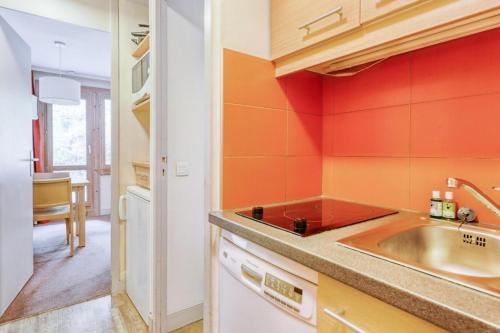 - une cuisine avec des murs orange et un évier dans l'établissement Résidence Plagne Lauze - maeva Home - Studio 2 personnes - Sélection MAE-9201, à Mâcot La Plagne