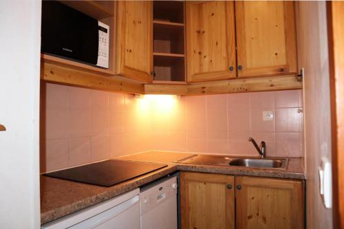 une cuisine avec des armoires en bois et un évier dans l'établissement Résidence Les Eglantines - B116 LES EGLANTINES 1800 MAE-4844, aux Orres