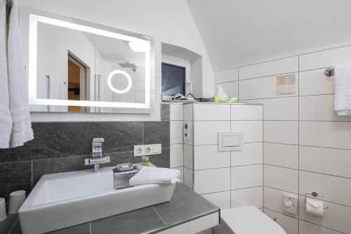 een witte badkamer met een wastafel en een spiegel bij Gästehaus "Ursula" Hotel Garni in Bernkastel-Kues