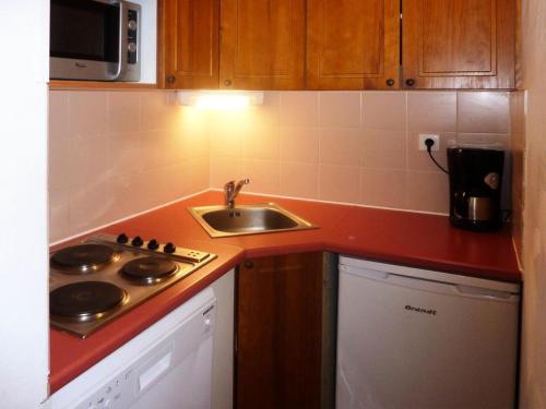 une petite cuisine avec un évier et une cuisinière dans l'établissement Résidence Les Erines - 1305 ERINES LES ORRES 1800 MAE-4834, aux Orres