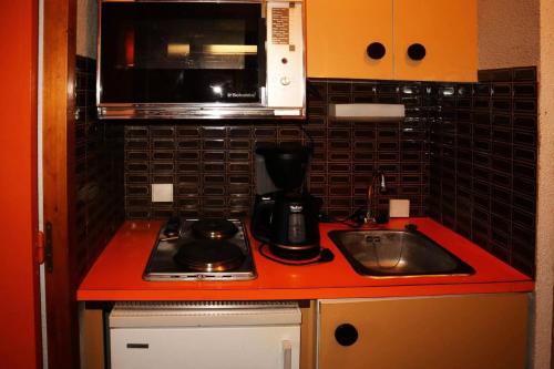 une cuisine avec une cuisinière, un évier et un micro-ondes dans l'établissement Résidence Le Belvedere - Mini studio 2 personnes MAE-7014, aux Orres