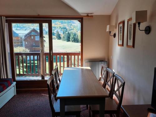 une salle à manger avec une table et des chaises et une grande fenêtre dans l'établissement Résidence L'Alpaga - maeva Home - Appartement 3 Pièces 7 Personnes - Budget MAE-2454, à La Salle Les Alpes