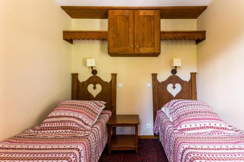 - 2 lits dans une chambre avec des cœurs sur le mur dans l'établissement Résidence L'Alpaga - maeva Home - Appartement 3 Pièces 7 Personnes - Budget MAE-2454, à La Salle Les Alpes
