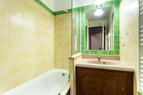 une salle de bain avec une baignoire, un lavabo et un miroir dans l'établissement Résidence L'Alpaga - maeva Home - Appartement 2 Pièces 5 Personnes - Budget MAE-2484, à La Salle Les Alpes