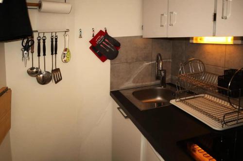 une cuisine avec un évier et un comptoir avec des ustensiles dans l'établissement Résidence Le Boussolenc - Studio équipé pour 4 personnes MAE-4144, aux Orres