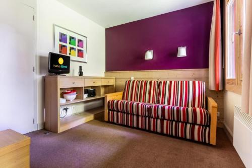 - un salon avec une chaise et un mur violet dans l'établissement Résidence Plagne Lauze - maeva Home - Studio 4 Personnes - Sélection MAE-3584, à Mâcot La Plagne
