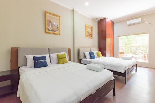 a bedroom with two beds and a window at Urbanview Resort Botol Cisarua Puncak Bogor in Tagalbato